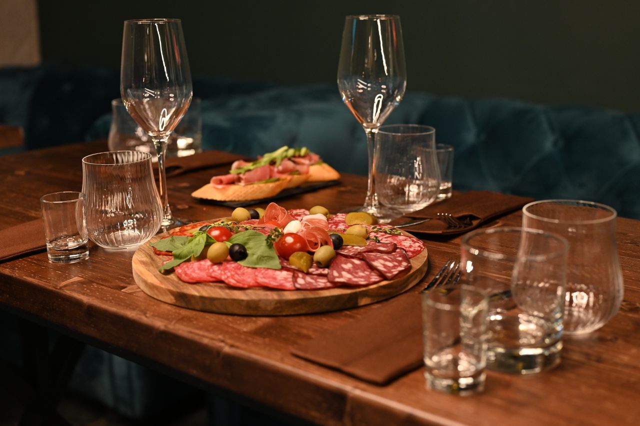Sophisticated charcuterie board with wine glasses on a wooden table creates a cozy dining ambiance.