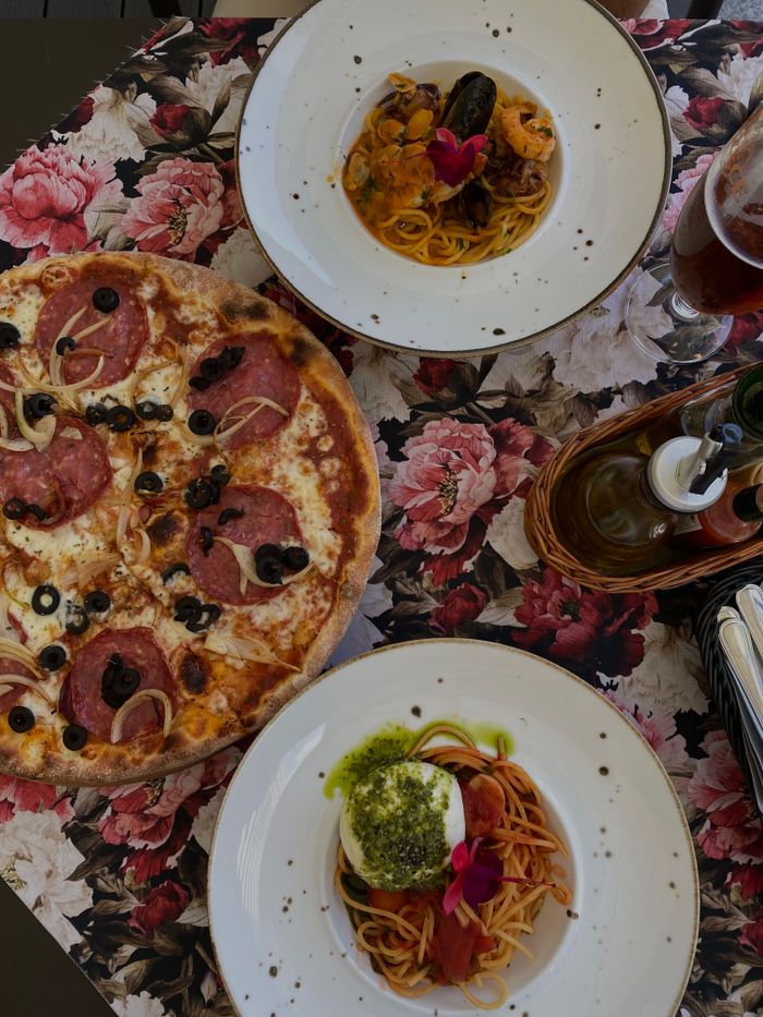 Mouth-watering pizza and pasta dishes beautifully arranged on a floral tablecloth in Poland.