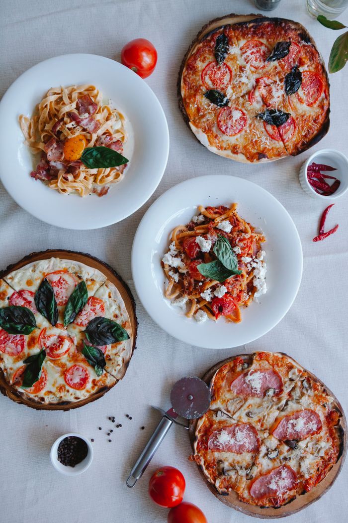 A tempting assortment of Italian pizzas and pasta dishes arranged beautifully on a table.